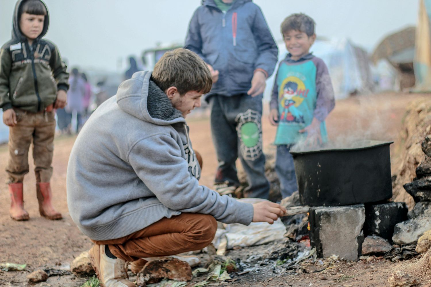 Kinder in einem Camp an einer Kochstelle